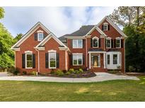 Stunning two-story red brick home featuring manicured lawn and lush landscaping at 620 Reeves Hill Pt, Lawrenceville, GA 30043