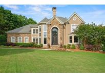 Inviting home with a manicured lawn, stone accents, and a grand entrance at 7025 Kettering Ln, Suwanee, GA 30024