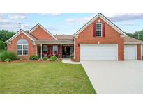 Charming brick home featuring a manicured lawn, inviting front porch, and an attached two-car garage at 1382 Fountain Lakes Drive Dr, Lawrenceville, GA 30043