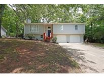 Charming split-level home featuring a spacious front yard, two-car garage, and inviting red stairway entrance at 4191 Alaina Cir, Austell, GA 30106