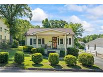 Charming home featuring mature landscaping, a cozy front porch, and a well-maintained lawn on a sunny day at 954 Bryant Sw St, Conyers, GA 30012