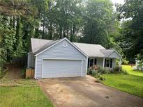 Charming single Gathering home with a two-car garage, manicured lawn, and mature trees at 185 Colemans Bluff Dr, Woodstock, GA 30188