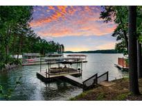 Picturesque lake view with a boat dock and beautiful sunset sky at 7875 Robin Rd, Cumming, GA 30041