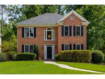 Charming two-story brick home with manicured lawn and mature trees, complete with black shutters and a classic front door at 1019 Legacy Walk, Woodstock, GA 30189