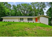 Charming white brick home with a bright orange door, situated on a lush green lawn at 3332 Saint John Dr, East Point, GA 30344