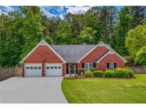 Charming, single-story brick home featuring a two-car garage, well-manicured lawn, and lush landscaping at 175 Prince Ct, Hiram, GA 30141
