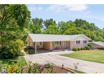 Charming brick home featuring a covered parking area, landscaped front yard, and mature trees at 701 Rosedale Se Dr, Smyrna, GA 30082