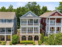 Charming three-story home featuring a double porch, gray siding, and beautiful landscaping at 2059 Wheaton Way, Atlanta, GA 30328