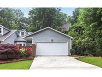 Attached two-car garage with a concrete driveway and gray siding surrounded by beautiful landscaping at 2983 Crosswycke Forest Dr, Brookhaven, GA 30319