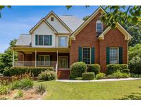 Charming two-story brick home with a welcoming front porch and lush, landscaped front yard at 3175 Lake Seminole Pl, Buford, GA 30519