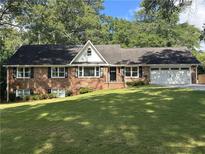 Charming brick home featuring a well-manicured lawn, a two-car garage, and traditional black window shutters at 1702 Montcliff Ct, Decatur, GA 30033