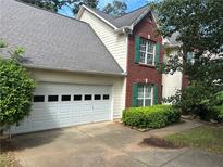 Traditional home featuring a brick facade, neutral siding, green shutters, and a two-car garage at 1570 Twin Bridge Ln, Lawrenceville, GA 30043