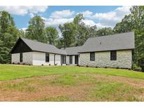 Beautiful exterior features a white painted brick, vertical siding, black trim, new roof, and manicured lawn at 2725 Glendale Ne Dr, Conyers, GA 30013