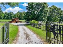 Scenic property featuring a gated entry, barn, and house, nestled amidst lush greenery and a gravel driveway at 1780 Penn Camp Road, Douglasville, GA 30134