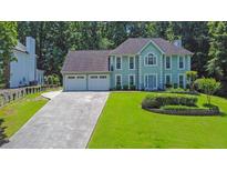 Attractive two-story home with a three-car garage and a well-maintained lawn, surrounded by mature trees at 985 Laurel Springs Ln, Marietta, GA 30064