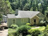 Charming single-story home featuring a stone facade, light green siding, and lush greenery in a tranquil wooded setting at 1268 Thomas Rd, Decatur, GA 30030