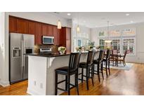 Modern kitchen with stainless steel appliances, breakfast bar and hardwood floors leading to the dining room at 1258 Dekalb Ne Ave # 112, Atlanta, GA 30307