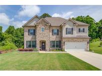 Beautiful two-story home featuring a combination of stone and siding, a manicured lawn, and an attached two-car garage at 4931 Pauls Pointe, Sugar Hill, GA 30518