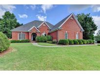 Beautiful brick home with a well-manicured lawn and mature landscaping under a bright blue sky at 1901 Paper Birch Cv, Grayson, GA 30017