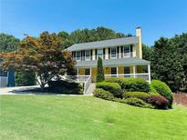Charming two-story home with yellow exterior, black shutters, and well-manicured lawn at 5425 Windswept Trce, Sugar Hill, GA 30518