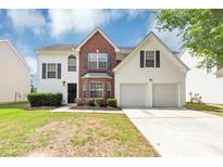 Charming two-story home featuring a brick facade, white siding, a two-car garage, and a well-manicured front yard at 11827 Spring Lake Way, Fayetteville, GA 30215