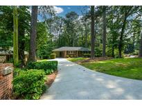 Charming brick home with a well-maintained yard and a long driveway surrounded by mature trees at 1376 Woodbine St, Marietta, GA 30062