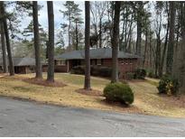 Charming brick home nestled among mature trees with a well-maintained front yard at 1376 Woodbine St, Marietta, GA 30062