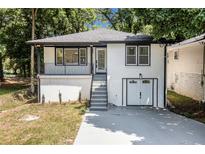 Charming renovated home with white brick, black trim, and an inviting front porch in a lush, wooded setting at 2537 Baker Nw Rd, Atlanta, GA 30318