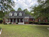 Traditional red brick home featuring dormer windows, a large covered porch, and well-manicured landscaping at 349 Bald Rock Rd, Oxford, GA 30054