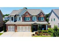 Inviting two-story home with a brick facade, three-car garage, landscaped front yard and charming curb appeal at 724 Laura Jean Ct, Buford, GA 30518