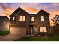 Two-story home featuring brick accents, a two-car garage, a manicured lawn, and colorful sunset at 1173 Gaines St, Jonesboro, GA 30238