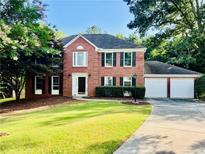 Traditional brick home with a well-manicured lawn, black shutters, and a two-car garage at 415 Wood Trace Ct, Alpharetta, GA 30022
