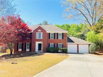 Charming two-story brick home with a well-maintained front yard and three-car garage at 415 Wood Trace Ct, Alpharetta, GA 30022