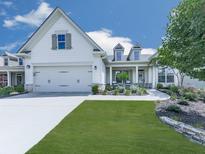 Charming exterior featuring white siding, a well-manicured lawn, and a two-car garage at 603 Canyon Overlook, Canton, GA 30114