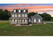 Inviting two-story home with a covered front porch and well-manicured lawn against a colorful sky at 615 Henderson Mill Rd, Covington, GA 30014