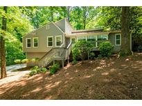 Charming home with a welcoming front porch and beautiful, mature trees surrounding the property at 148 Bramble Oak Dr, Woodstock, GA 30188