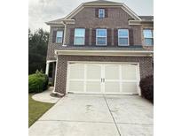 Two car garage with white doors and brown brick exterior at 5850 Shiloh Woods Dr, Cumming, GA 30040