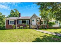 Charming brick home featuring a stone accent entrance, well-manicured lawn, and mature trees under a bright, sunny sky at 1544 Brewer Sw Blvd, Atlanta, GA 30310