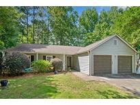 Charming single-story home with a two-car garage and lush landscaping in a serene, wooded setting at 10650 Colony Glen Dr, Johns Creek, GA 30022