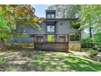 Stunning modern home with a wooden porch, stone accents, a green door, and surrounded by lush greenery at 945 Tiber Cir, Alpharetta, GA 30022