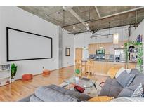 Modern loft with an open floor plan, hardwood floors, exposed ductwork, and a large projector screen at 3235 Roswell Ne Rd # 702, Atlanta, GA 30305