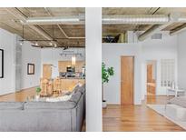 Bright open-concept living room featuring exposed pipes, hardwood floors, and sight lines into the kitchen and bathroom at 3235 Roswell Ne Rd # 702, Atlanta, GA 30305