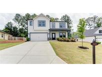 Charming two-story home featuring a spacious driveway, landscaped yard, and modern architectural details at 3410 Summerpoint Xing, Cumming, GA 30028