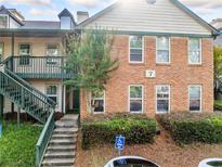 Brick exterior featuring stairs to condo unit, greenery and parking area at 705 Beaufort Cir, Duluth, GA 30096