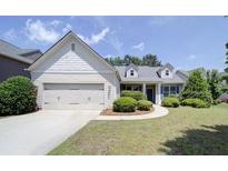 Charming one-story home with a well-manicured lawn, a two-car garage and complemented by lush green landscaping at 1575 Parkside Village Dr, Cumming, GA 30040