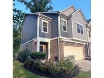 Charming two-story townhome featuring a brick facade, attached garage, and well-manicured landscaping at 201 Jonquil Spring Rd, Woodstock, GA 30188