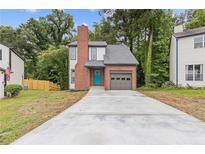Charming two-story home boasts a brick chimney, attached garage, and vibrant blue front door at 1111 Pin Oak Dr, Tucker, GA 30084