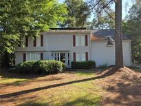 Traditional two-story home with light siding, manicured bushes and mature trees at 2344 Country Club Se Dr, Conyers, GA 30013