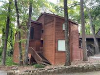 Charming two-story home with wood facade surrounded by mature trees and stone retaining wall at 2449 Terrace Trl, Decatur, GA 30035