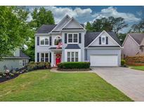 Charming two-story home with a well-manicured lawn, a red door, and a two-car garage at 4174 Chatham Crest Ln, Buford, GA 30518